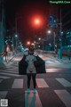 A woman standing in the middle of a street at night.