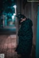 A woman wearing a black mask standing in an alleyway.