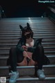 A woman wearing a cat mask sitting on some stairs.