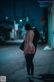 A woman standing in the middle of a street at night.