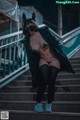 A woman wearing a black cat mask sitting on some stairs.