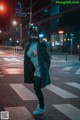 A woman wearing a cat mask standing in the middle of a street.