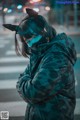 A woman wearing a camouflage jacket and a mask.