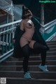 A woman in a black cat mask is sitting on some stairs.