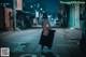 A woman in a black dress is walking down the street.