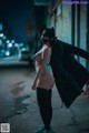 A woman in a black cat costume is standing on the street.