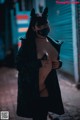 A woman wearing a black cat mask standing in an alleyway.