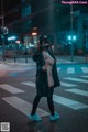 A woman in a cat mask is standing in the middle of the street.