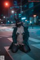 A woman wearing a mask sitting on the ground in the middle of a street.