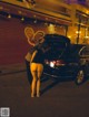 A woman standing next to a black car on a city street.