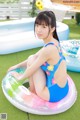 A woman in a blue swimsuit sitting on an inflatable ring.