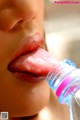 A close up of a woman's tongue sticking out of a bottle.