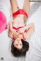 A woman in a red lingerie laying on a bed.