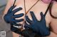 A woman in a black bra top and blue gloves.