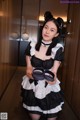 A woman in a black and white maid outfit holding a pair of shoes.