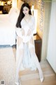 A woman in a white lingerie posing in a hotel room.