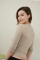 A woman in a beige sweater is posing for a picture.