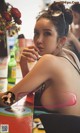 A woman sitting at a table with a drink in her hand.