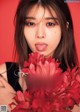 A woman holding a bunch of red flowers in front of her face.