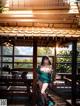 A woman in a green dress standing on a wooden deck.