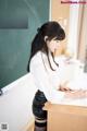 A woman sitting at a desk writing on a piece of paper.