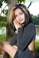 A woman sitting on a bench next to a tree.