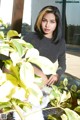 A woman sitting on top of a table next to a plant.