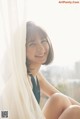 A woman sitting on a window sill smiling at the camera.