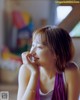 A woman sitting on a couch with her hand on her chin.