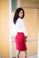 A woman in a white shirt and red skirt posing for a picture.