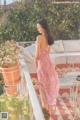 A woman in a pink dress standing on a balcony.