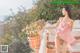 A woman in a pink dress sitting on a balcony.