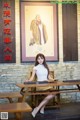 A woman sitting at a table in front of a painting.