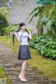 A woman in a blue shirt and black skirt standing on some steps.