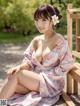 A woman in a pink kimono sitting on a wooden bench.