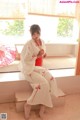 A woman in a white kimono sitting on a window sill.