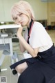 A woman with pink hair sitting at a desk.