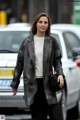 A woman walking down the street in a black and white coat.