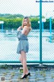 A woman standing in front of a chain link fence.