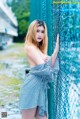 A woman in a blue and white striped dress leaning against a fence.