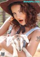 A woman in a cowboy hat holding a baby goat.