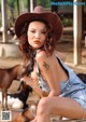 A woman in a cowboy hat sitting on a wooden bench.