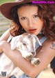 A woman in a cowboy hat holding a baby goat.