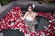 A woman in a white dress sitting in a pool of rose petals.