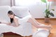 A woman in a white bodysuit laying on a white couch.