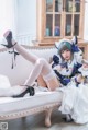 A woman in a maid outfit is sitting on a couch.