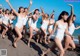 A group of women in white bathing suits running on the beach.