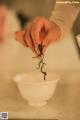 A person holding a small plant in a white bowl.