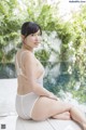 A woman in a white bathing suit sitting on the edge of a pool.