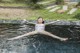 A woman floating in a pool with her arms outstretched.